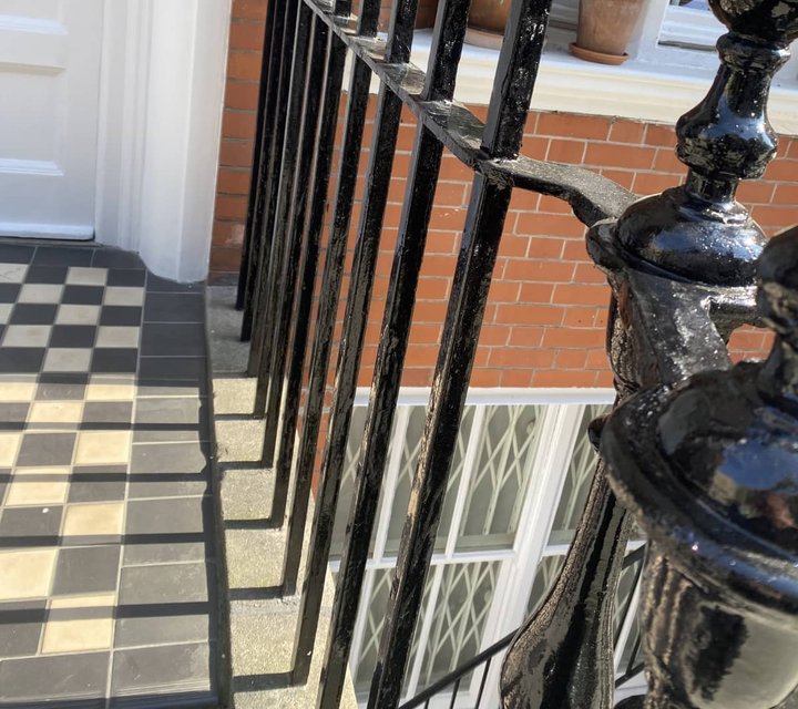 Gloss-black painted iron railings beside a white-painted entrance
