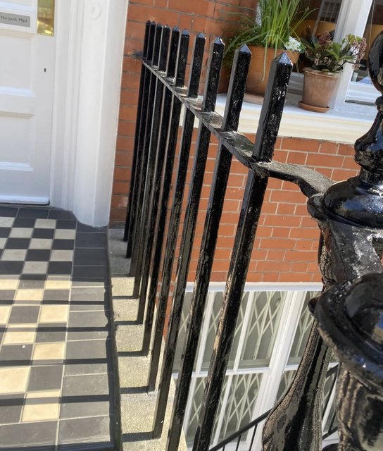 Gloss-black painted iron railings beside a white-painted entrance
