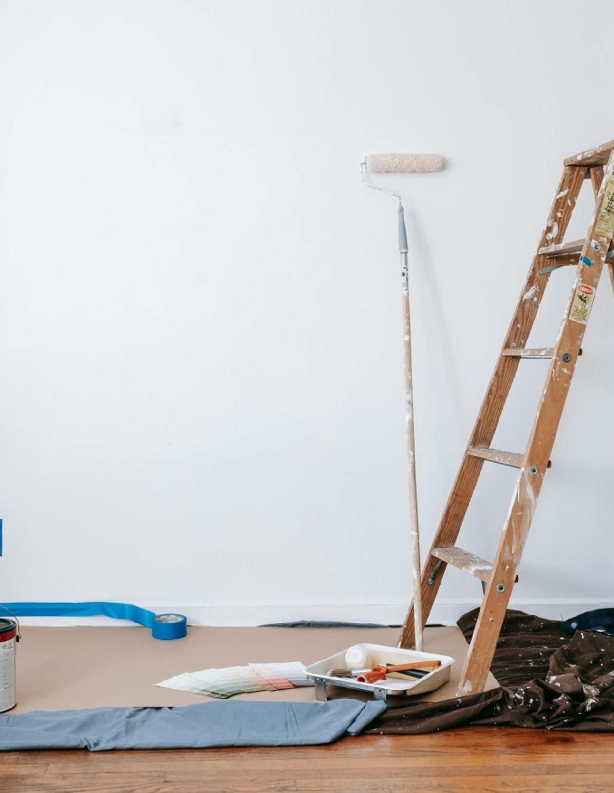 Painting tools and a ladder beside a freshly painted interior wall