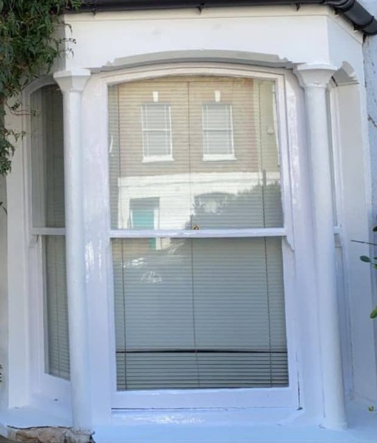 Freshly painted white bay-window frame and decorative surround